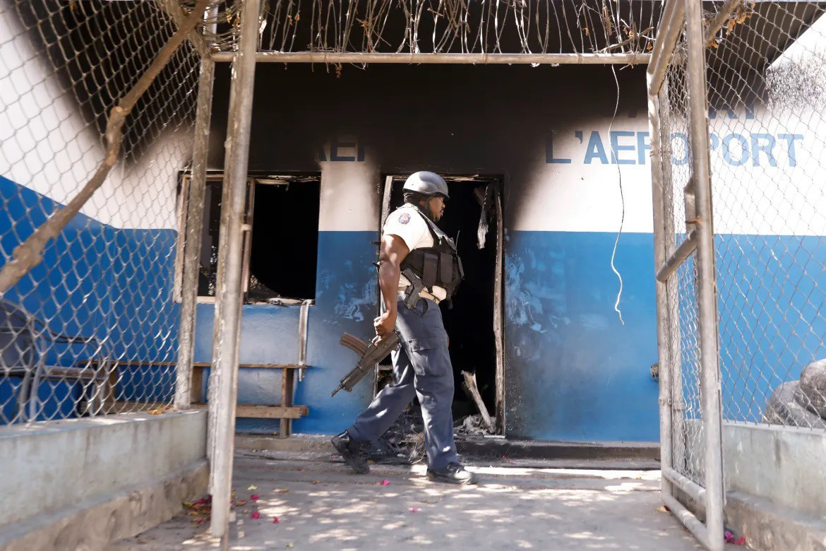 Cảnh sát Haiti phòng thủ ở một đồn cảnh sát bị đốt phá (ảnh : Al Jazeera)