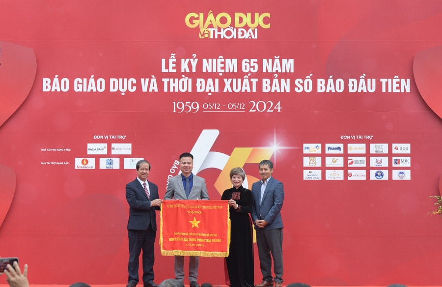 Bộ trưởng Nguyễn Kim Sơn trao Cờ thi đua của Chính phủ cho Báo Giáo dục và Thời đại dịp kỷ niệm 65 năm ngày Báo Giáo dục và Thời đại xuất bản số báo đầu tiên. Ảnh: Trần Hiệp
