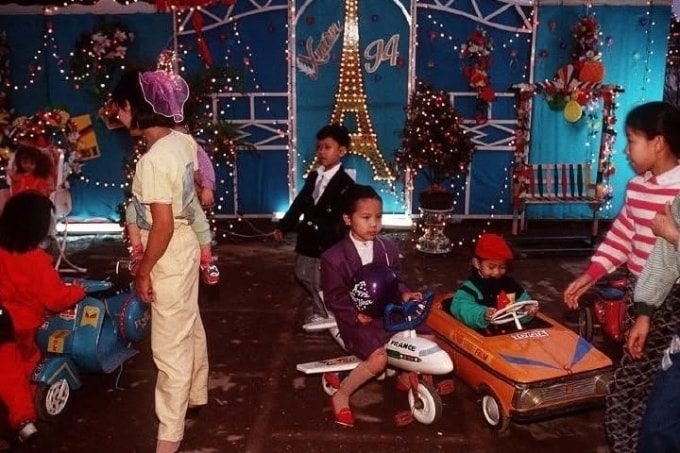 Một khu vui chơi thời ấy với các đồ chơi mô phỏng ôtô, xe máy, máy bay. Trẻ em thành phố mặc trang phục rực rỡ, gọn gàng trong ngày Tết.