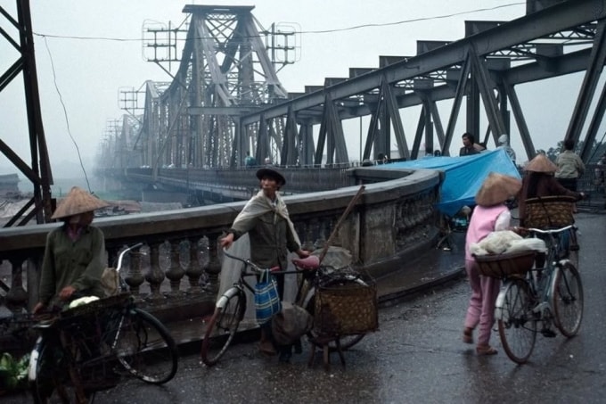 Những người bán hàng rong đội nón lá, khoác áo mưa đi trên cầu Long Biên.