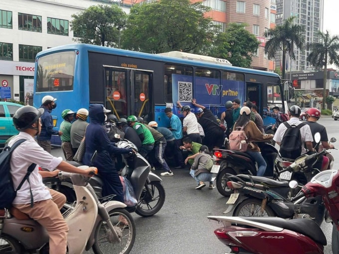 Hơn chục người nâng xe buýt cứu cô gái mắc kẹt dưới gầm xe. Ảnh: Xuân Hoa