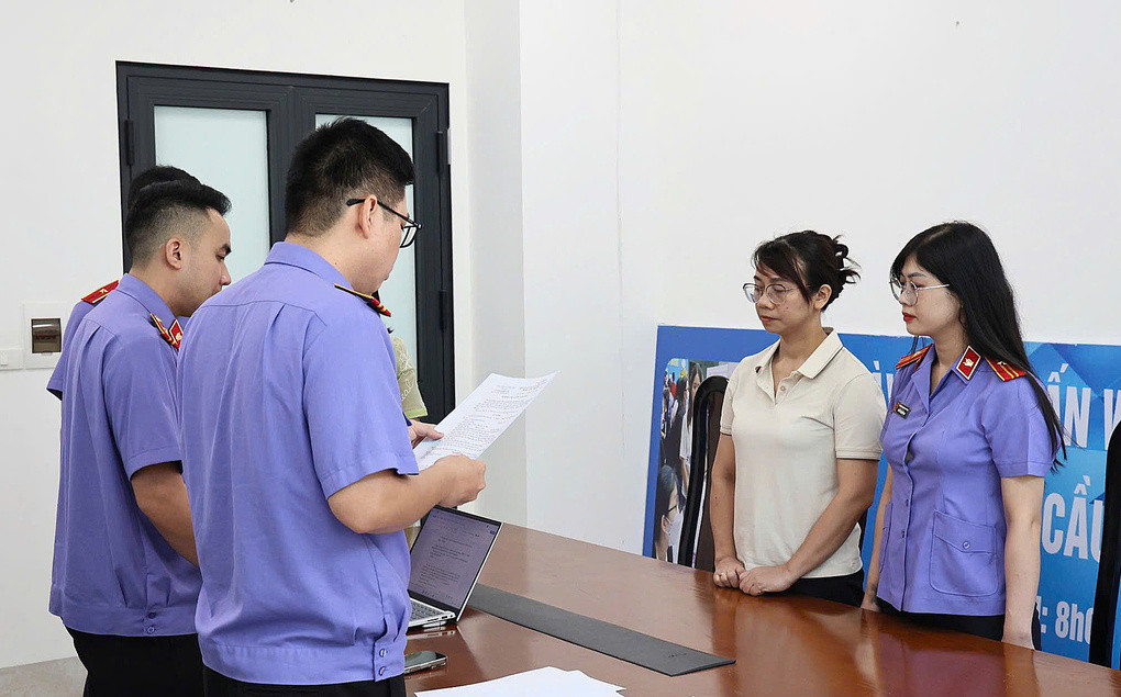 Cơ quan điều tra VKSND tối cao thi hành lệnh khởi tố với một bị can là cựu kiểm sát viên (áo trắng). Ảnh: Linh Đan