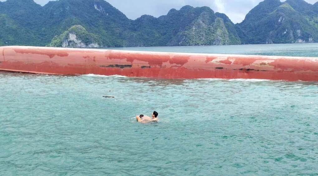 Hai thuyền viên Bùi Văn Nhớ và Nguyễn Văn Cương cạnh tàu hàng bị lật. Ảnh: Văn Chương