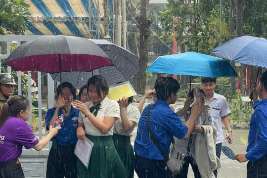 Tình nguyện viên đội mưa che ô cho thí sinh tại Bình Dương